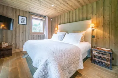 a bedroom with a white bed and a television at Chalet des Ours I Le Chalet Club in Megève