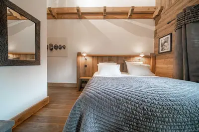 a bedroom with a large bed and a mirror at Chalet des Ours I Le Chalet Club in Megève