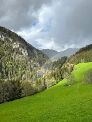 a green field with a rainbow in the distance at chalet du Champel jacuzzi in Saint-Gervais-les-Bains