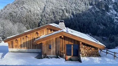 a log cabin in the snow with a chimney at chalet du Champel jacuzzi in Saint-Gervais-les-Bains