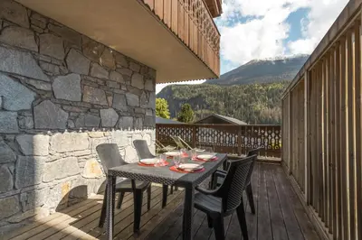 a table and chairs on a patio with a stone wall at Appartement Bellevue Au pied des pistes in Les Houches
