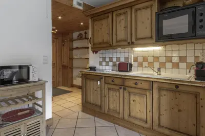 a kitchen with wooden cabinets and a microwave at Appartement Bellevue Au pied des pistes in Les Houches