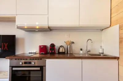 a kitchen with white cabinets and a stove and a sink at Chailloud - Modern Studio 2pax - Lively Area - TV Wifi in Chamonix-Mont-Blanc