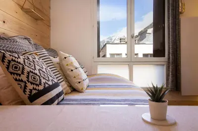 a room with a bed with pillows and a window at Chailloud - Modern Studio 2pax - Lively Area - TV Wifi in Chamonix-Mont-Blanc