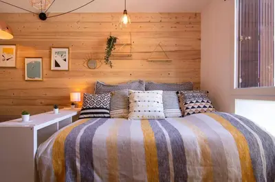 a bedroom with a bed with a wooden wall at Chailloud - Modern Studio 2pax - Lively Area - TV Wifi in Chamonix-Mont-Blanc