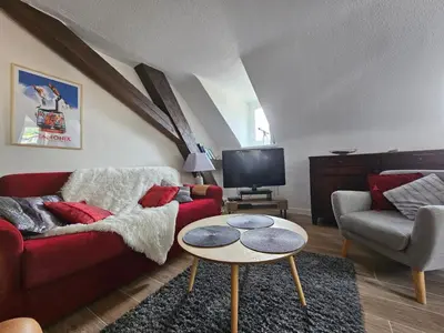 a living room with a red couch and a table at Appartement hyper centre, idéal pour 4 pers possibilité 6 couchages in Chamonix-Mont-Blanc