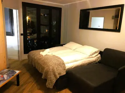 a bed in a room with a couch and a mirror at Base Camp Chamonix Vue Mont Blanc Centre Ville in Chamonix-Mont-Blanc