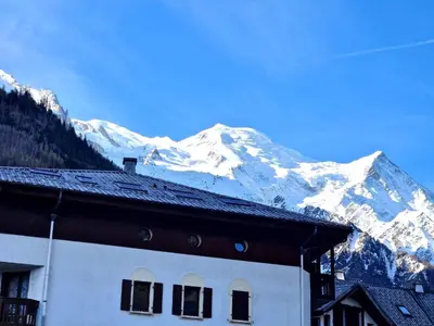 a building with a snow covered mountain in the background at Base Camp Chamonix Vue Mont Blanc Centre Ville in Chamonix-Mont-Blanc