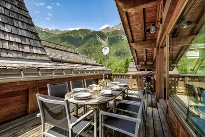 a table and chairs on the balcony of a cabin at Chalet d'Olivier - Alpes Travel - Les Praz (Sleeps 8) in Chamonix-Mont-Blanc