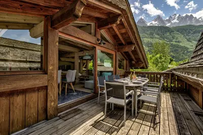a wooden deck with a table and chairs on it at Chalet d'Olivier - Alpes Travel - Les Praz (Sleeps 8) in Chamonix-Mont-Blanc