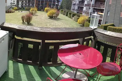 a pink table and a chair on a balcony at Appartement rénové avec parking plein centre in Samoëns