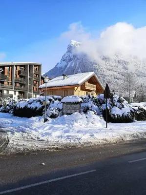 a house with a mountain in the background with snow at Appartement rénové avec parking plein centre in Samoëns