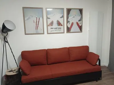 a couch in a living room with pictures on the wall at Appartement rénové avec parking plein centre in Samoëns