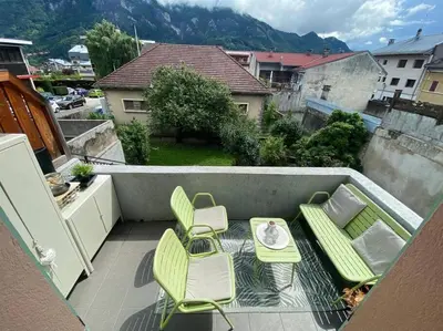 a balcony with green chairs and a table and chairs at Appartement au pays du Mont-Blanc in Sallanches