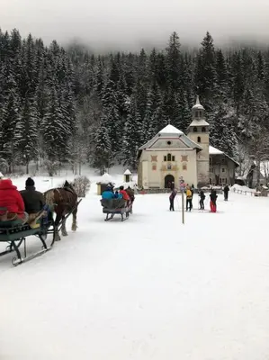 a group of people riding in a horse drawn carriage in the snow at Appartement au pays du Mont-Blanc in Sallanches