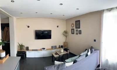 a living room with a couch and a tv on a wall at Appartement au pays du Mont-Blanc in Sallanches