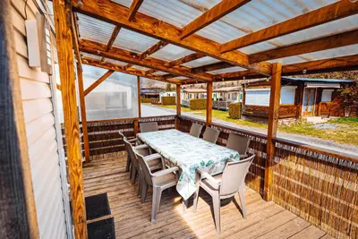 a patio with a table and chairs on a deck at Bungalow 3 chambres pour 6 pers avec Climatisation Camping 3 etoiles in Samoëns