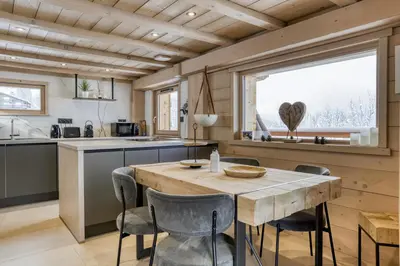 a kitchen with a wooden table and chairs at Chalet neuf La Perle du Perron in Cordon